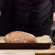 man in black uniform, put a metal baking tray on the table with baked round bread - VideoHive Item for Sale
