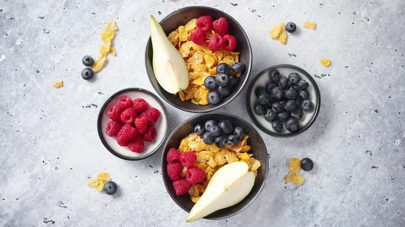 Golden Cornflakes with Fresh Fruits of Raspberries, Blueberries and Pear in Ceramic Bowl
