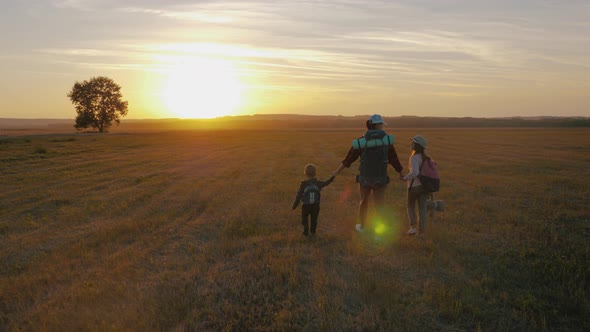 Silhouettes of Mother with Two Kids Hiking on Nature on Sunset