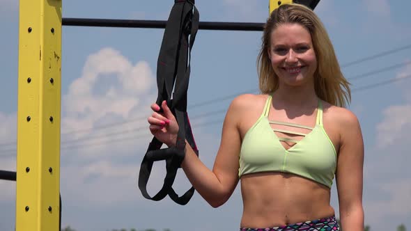 A Fit Beautiful Woman Stands By Gym Ropes at an Outdoor Gym and Smiles at the Camera - Closeup