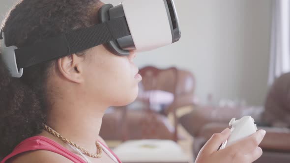 Portrait of African American Woman Wearing in the Virtual Reality Headset Using Joystick Sitting on