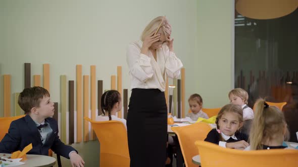 Exhausted Young Beautiful Woman Holding Head in Hands As Schoolchildren Yelling Around
