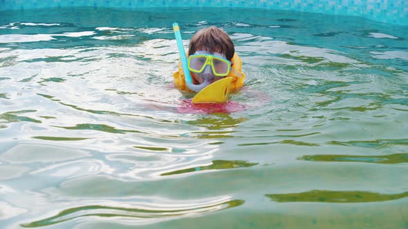 A Little Boy Swimming and Playing with a Toy Boat in the Pool