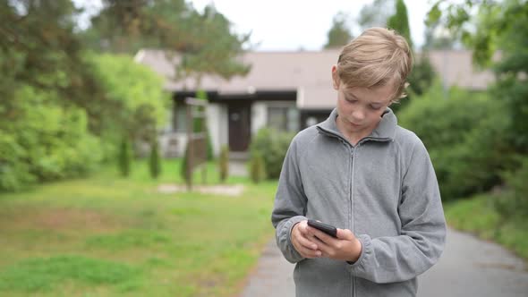 Young Boy Using Phone And Taking Selfie At Home Outdoors