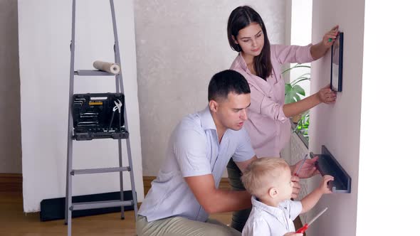 Father Teaches Little Son To Bolt Shelf To Wall with Screwdriver While Repairing Apartment