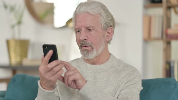 Old Man Celebrating on Smartphone at Home