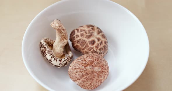 Adding water into white bowl with chinese dry mushroom