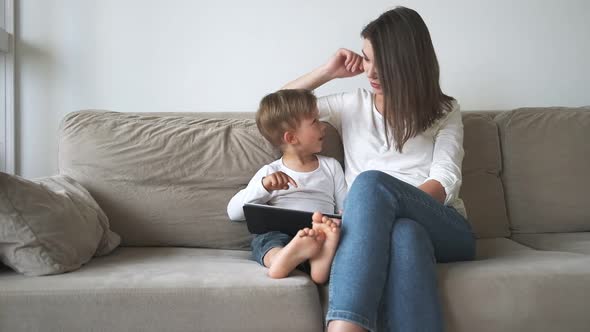 Family Mother and Child Using Tablet Sitting on Sofa at Home