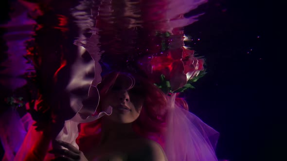 Close-up of a Woman's Face, Large Flowers and Reflections in the Surface of Dark Water. Purple