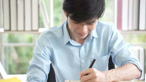 Asian young man seller entrepreneur checking online order selling on website confirming e-commerce
