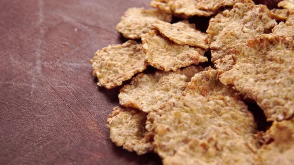 Breakfast cereals texture. Macro. Dry grain wheat flakes on a brown wooden surface