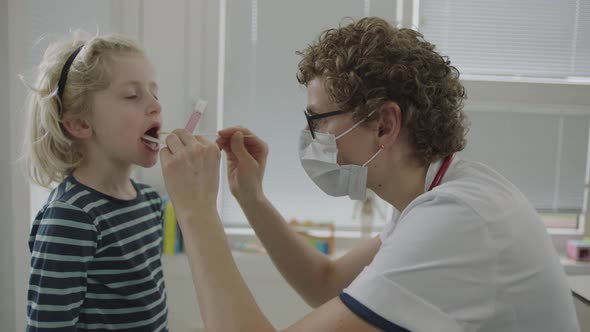 Doctor In Mask Using Swab To Test For Coronavirus On Little Boy