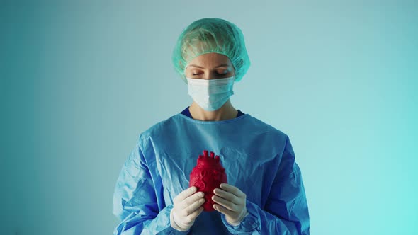 Young Caucasian Surgeon Holding a 3d Artifficial Heart Model and Showing It to the Camera