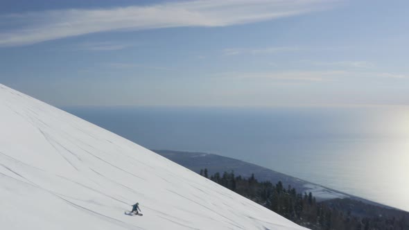 Snowboarder Riding on Downhill in Winter Resort at Sunny Day View From Drone