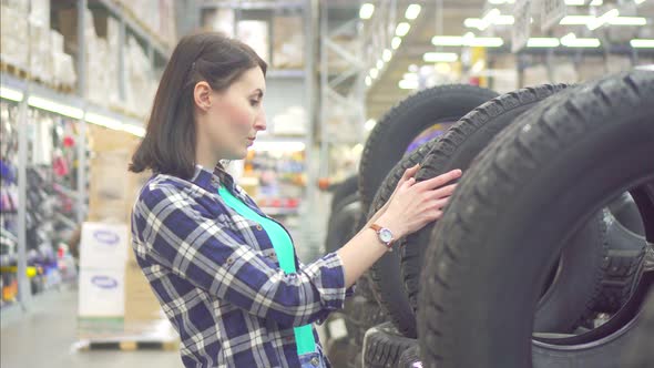 Girl in a Plaid Shirt Buys Spike Winter Tires in a Store