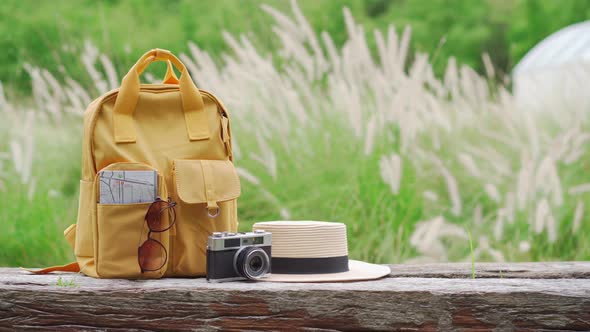 Travel backpack with traveler items on wooden bench with nature background