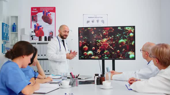 Specialist Medic Explaining Virus Development Pointing on Monitor