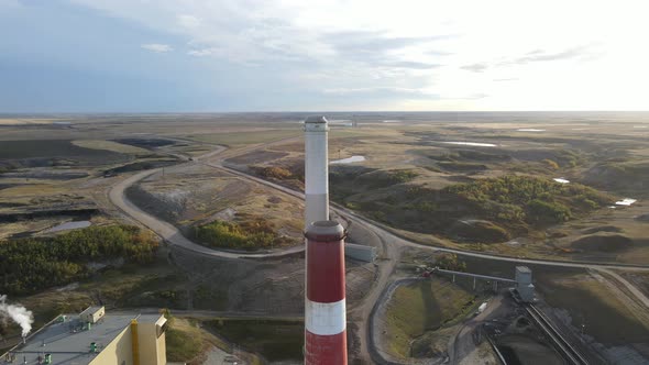 4k backwards drone flight over generating station in north american countryside during colourful sun