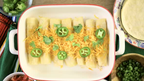 Chicken enchiladas with cheddar cheese and sauce.