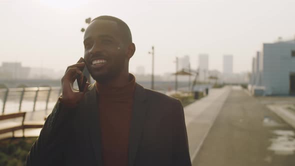 Young Black Businessman Walking on Street and Speaking on Phone