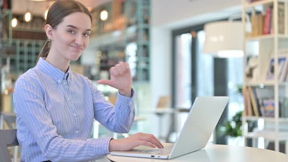 Thumbs Down By Young Businesswoman Using Laptop in Cafe