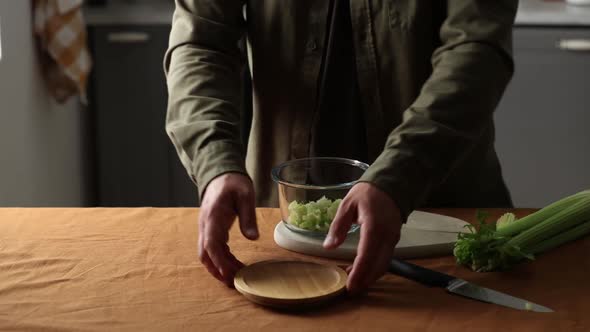 vegetarian man cuts Celery on a chalkboard in the kitchen with a knife