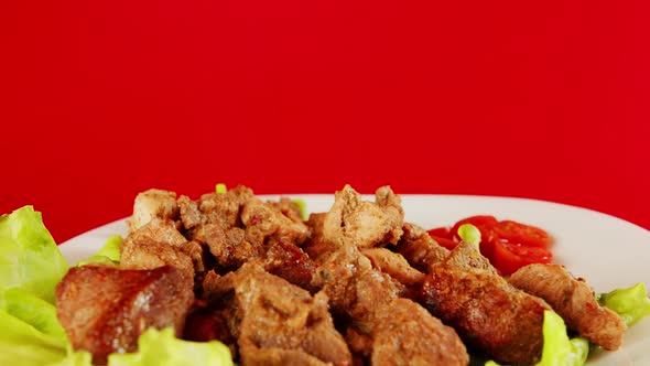 Pieces of meat in a white plate on lettuce leaves and cherry tomatoes