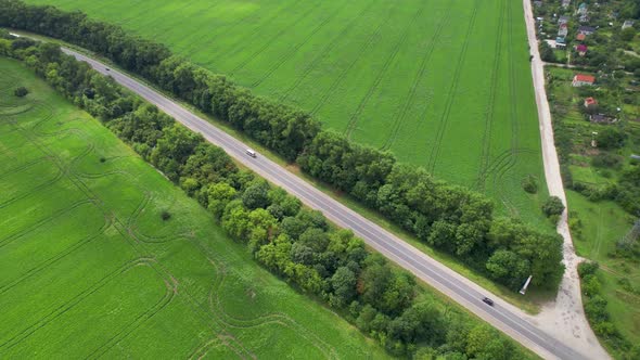 Aerial Drone Footage Flying Around a Road with Mooving Cars That Spans Over a Luscious Green Valley