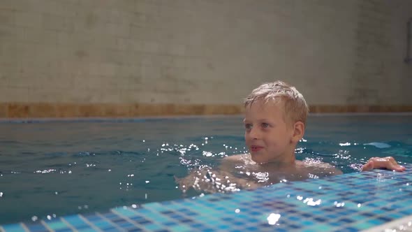 A Cute Boy is Swimming in the Swimming Pool at the Hotel