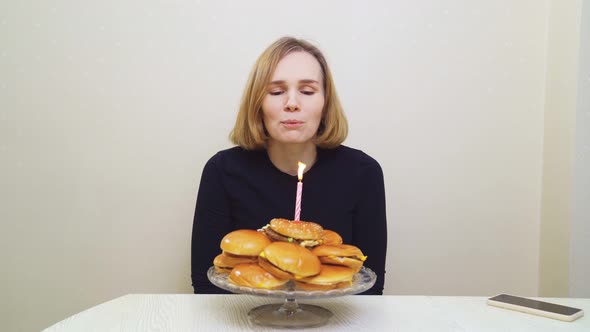 a Woman Makes a Wish and Blows Out a Candle on a Hamburger Cake