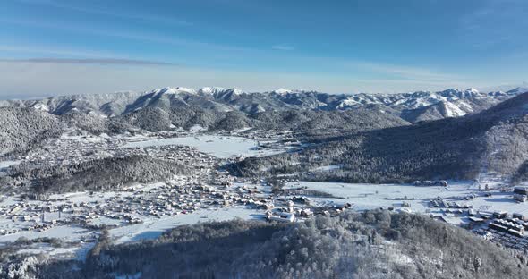 Aerial view of snow covered Bakuriani with beautiful snowy mountains around. Georgia 2021