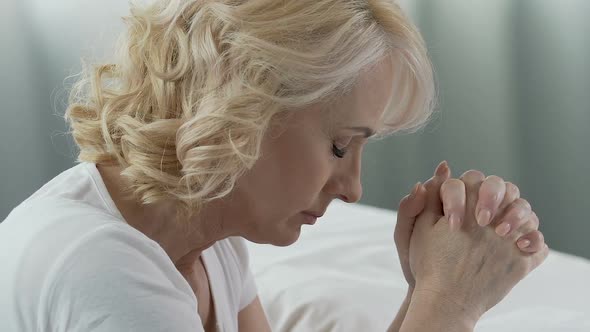 Elderly Female Praying Devotedly at Her Bed, Asking for Help, Serious Disease