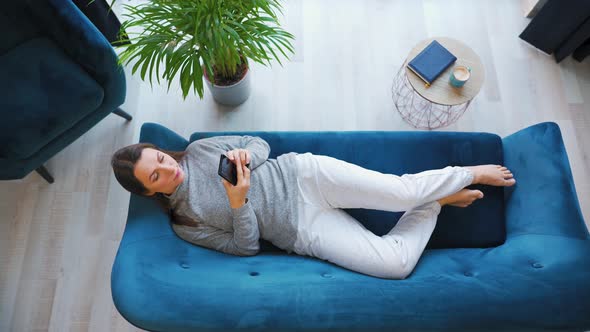 Overhead Shot of Happy Relaxed Woman Holding Smart Phone Using Mobile Apps Watching Funny Video