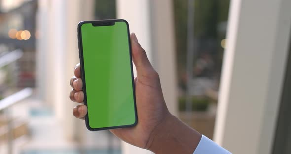 Close Up View of Afro American Man Hand Holding Smartphone with Mock Up screen.Concept of Green