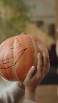 A Young Lady is Holding a Pumpkin and Smiling