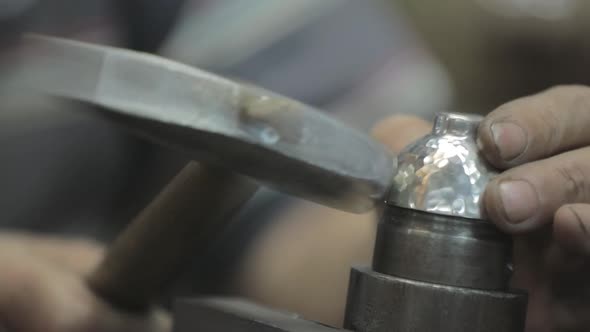 Silver work jeweler finish making Judaica silver cup, take the cup off, hammer dents. close-up