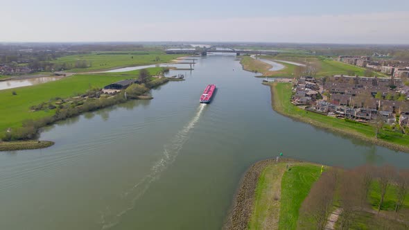 Reversing rising aerial view of red boat on ricer in Dutch countryside