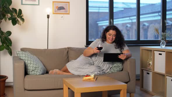 Woman with Tablet Pc Drinking Red Wine at Home