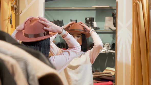 Beautiful Woman Trying on a New Hat, While Shopping at Clothing Store