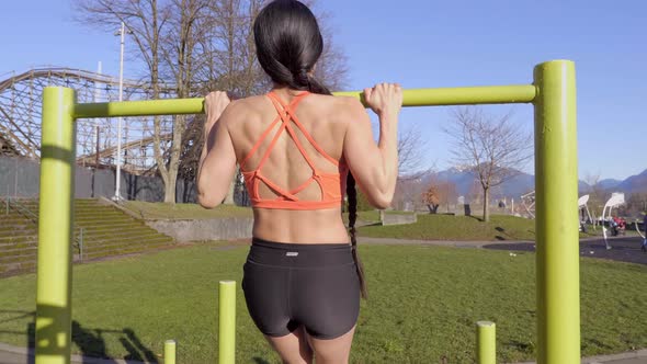 Young athletic woman doing pull-ups outdoor Medium wide shot