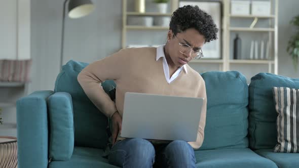 African Girl Grabbing Her Waist While Working on Laptop