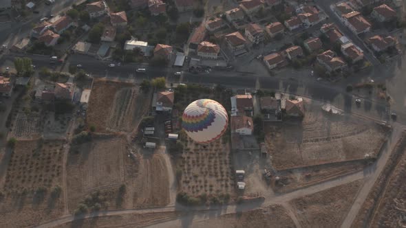 Large Hot Air Balloon Flies Over Brown Roof Buildings