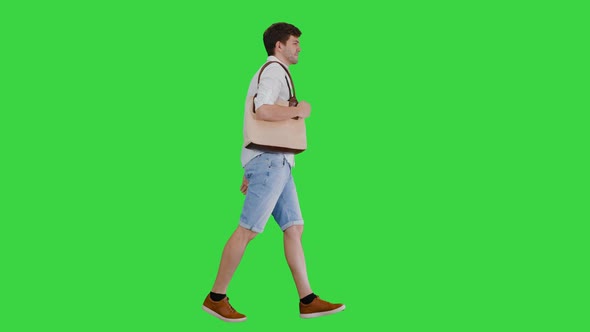 Handsome Smiling Man in White Shirt Walking with a Bag on His Shoulder on a Green Screen, Chroma Key