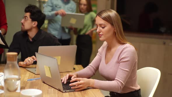 Tracking Shot of Focused Young Business Woman Sitting at Office Desk and Working on Laptop While