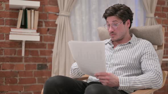 Middle Aged Man Reacting to Loss on Documents, Sofa