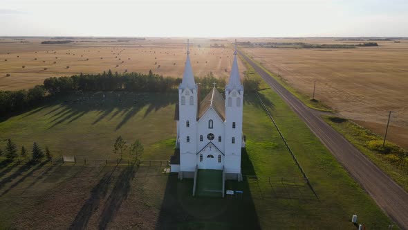 Aerial footage of St Peters roman catholic church in prairie during sunset. White building with blue