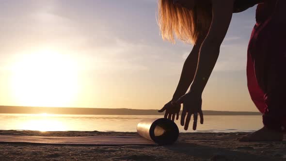 Close Up of a Yogi Woman Unfolding Yoga Mat on a Sand Near the Water