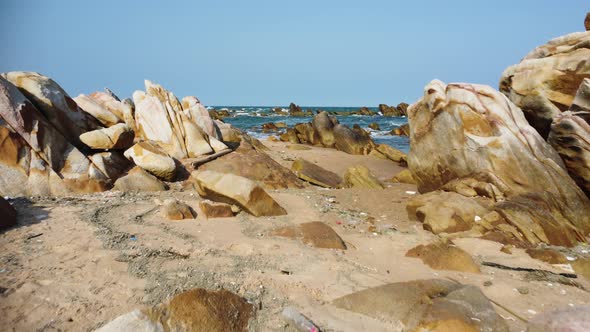 Sandy beach with rocks polluted with washed out rubbish, low altitude gimbal