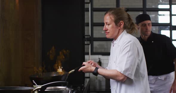 Caucasian female chef teaching diverse group preparing dishes and smiling