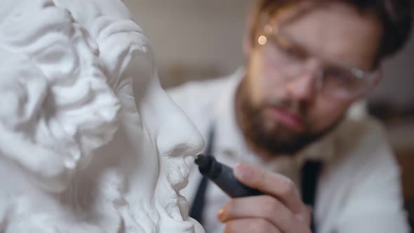 Male Master with Beard Working with Polishing Tool and Handmade Sculpture's Head